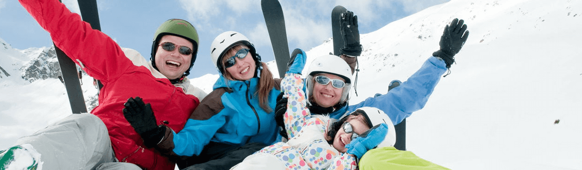 Three people wearing skis and helmets are smiling.