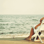 A person sitting on a beach chair near the ocean.