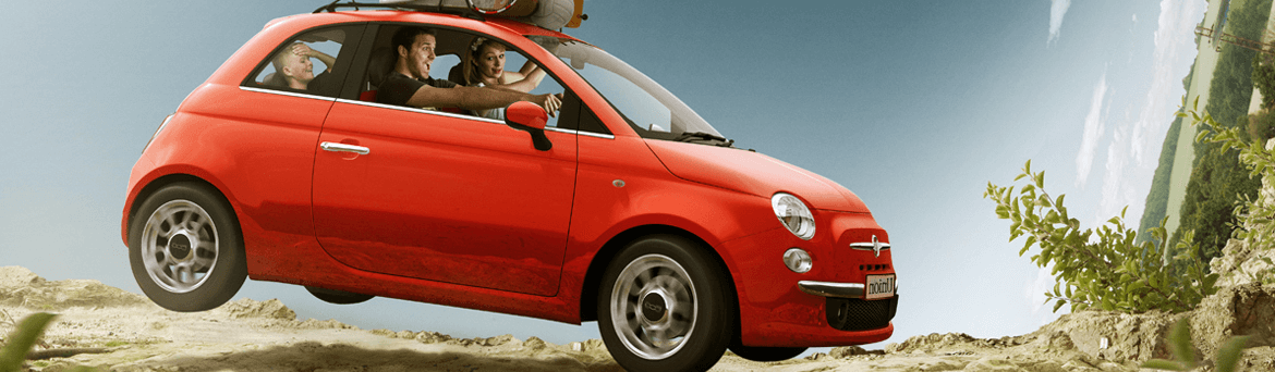 A woman driving in a red car with luggage on the roof.